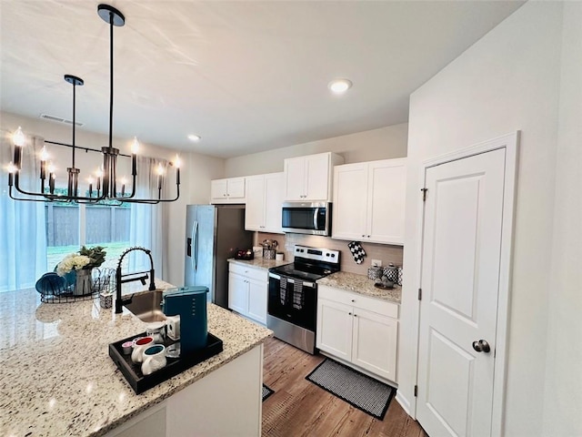 135 Softwood Ct, Dawsonville, GA 30534 - kitchen featuring stainless steel appliances, a chandelier, white cabinets, light wood-type flooring, and light stone countertops