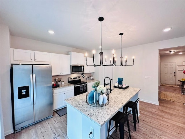 135 Softwood Ct, Dawsonville, GA 30534 - kitchen with appliances with stainless steel finishes, white cabinets, light wood finished floors, a center island with sink, and recessed lighting