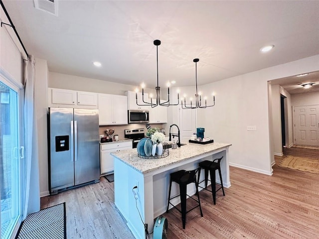 135 Softwood Ct, Dawsonville, GA 30534 - kitchen featuring stainless steel appliances, a chandelier, white cabinetry, light wood-style floors, and a kitchen breakfast bar