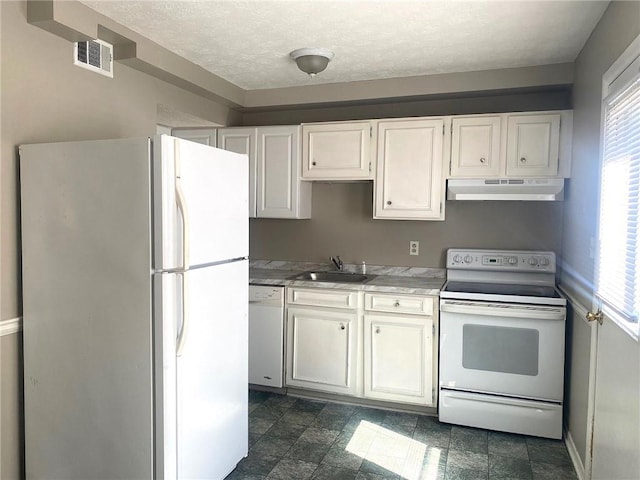 kitchen featuring white cabinets, dark tile patterned floors, white appliances, and sink