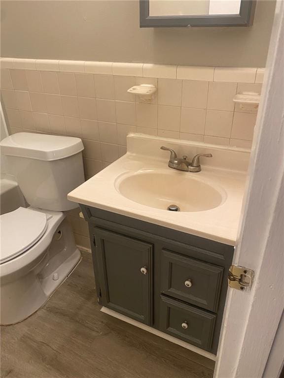 bathroom featuring tasteful backsplash, tile walls, toilet, vanity, and wood-type flooring