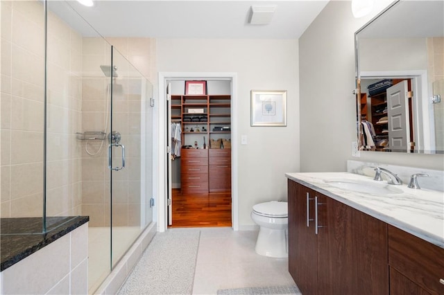 bathroom featuring walk in shower, vanity, toilet, and tile patterned flooring