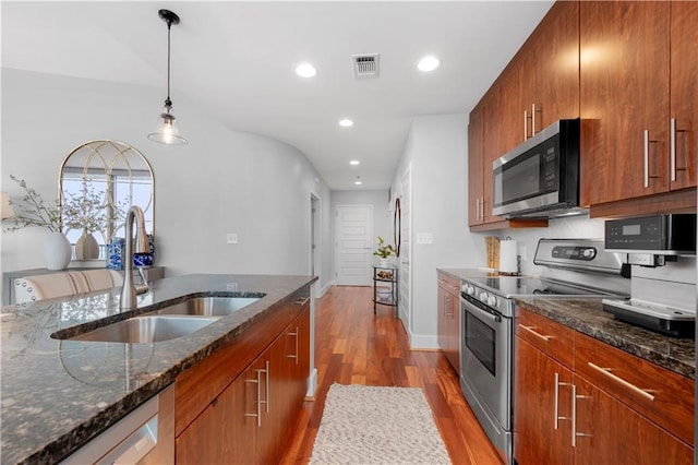 kitchen featuring decorative light fixtures, sink, dark stone countertops, light hardwood / wood-style floors, and stainless steel appliances