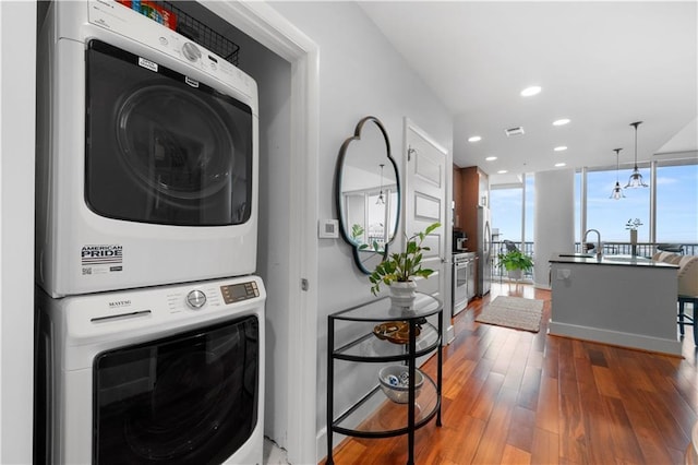 clothes washing area featuring stacked washing maching and dryer and hardwood / wood-style floors