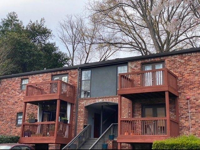 rear view of house with brick siding and a balcony