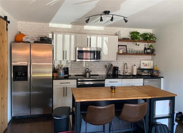 kitchen with tasteful backsplash, stainless steel appliances, a barn door, and white cabinets