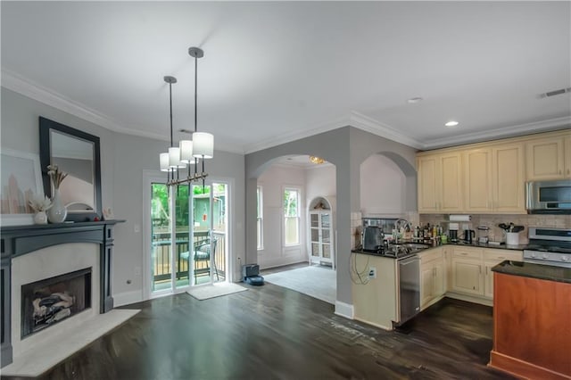 1786 Dekalb Ave NE, Atlanta, GA 30307 - kitchen with stainless steel appliances, cream cabinetry, dark countertops, dark wood-style floors, and arched walkways