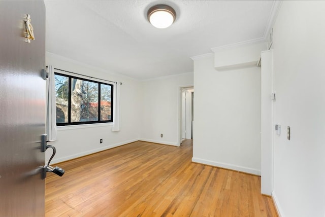 empty room featuring crown molding and light hardwood / wood-style floors