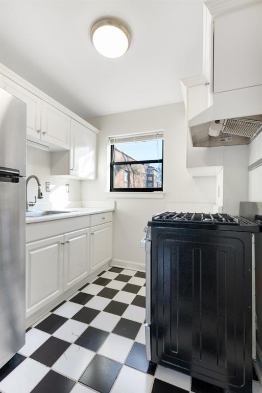 kitchen with premium range hood, sink, stainless steel refrigerator, range with gas stovetop, and white cabinets