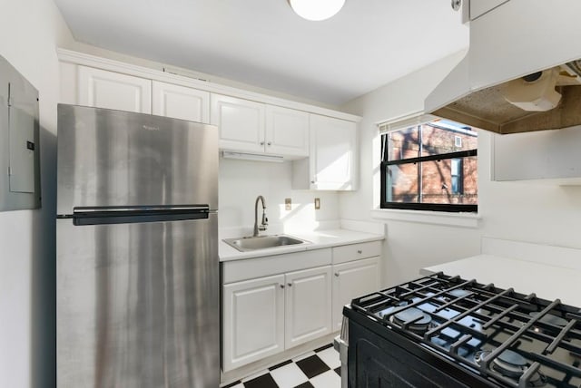 kitchen featuring sink, gas stove, stainless steel refrigerator, and white cabinets