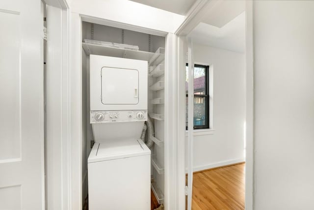 clothes washing area featuring stacked washer and dryer and wood-type flooring