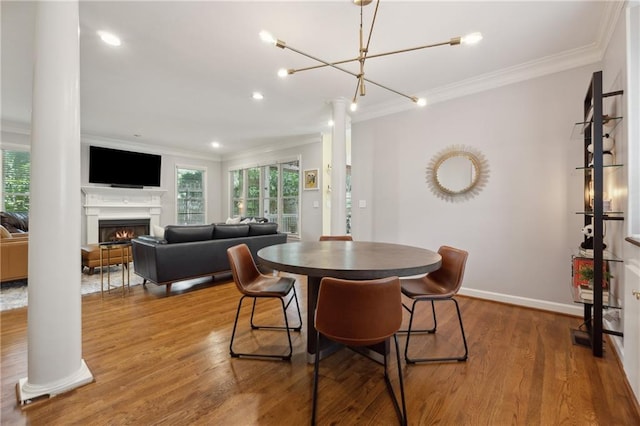 dining room with decorative columns, crown molding, wood-type flooring, and an inviting chandelier