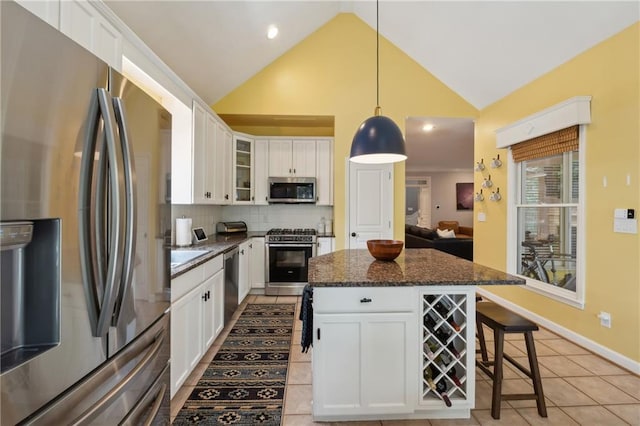 kitchen with white cabinets, a center island, dark stone countertops, and appliances with stainless steel finishes