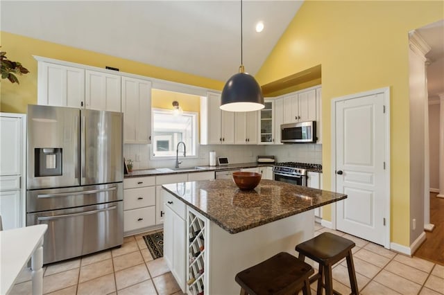 kitchen with decorative backsplash, stainless steel appliances, white cabinetry, a kitchen island, and lofted ceiling