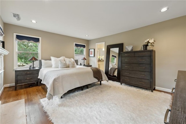 bedroom featuring hardwood / wood-style floors, connected bathroom, and multiple windows