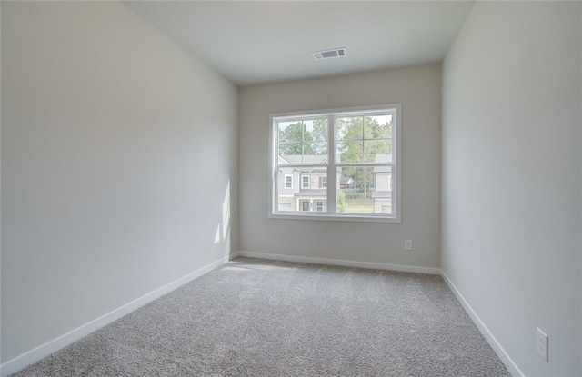 carpeted spare room featuring visible vents and baseboards