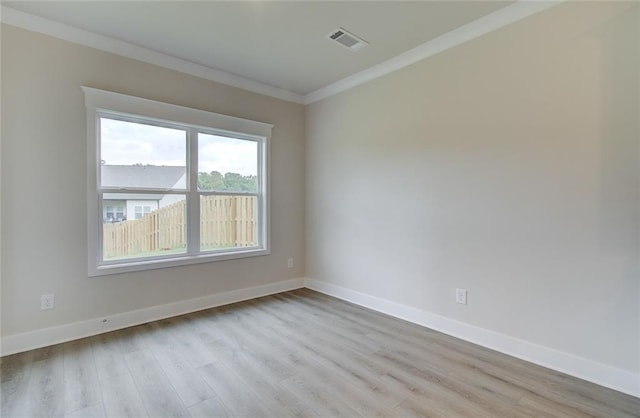 unfurnished room with visible vents, light wood-style flooring, baseboards, and ornamental molding