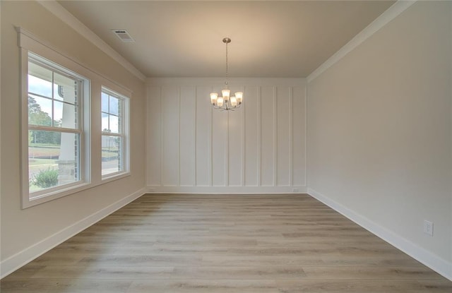 empty room with baseboards, visible vents, light wood finished floors, ornamental molding, and a notable chandelier