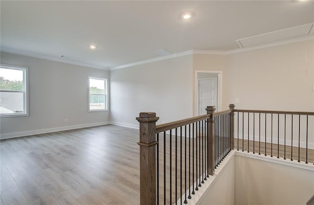 corridor with an upstairs landing, ornamental molding, wood finished floors, baseboards, and attic access