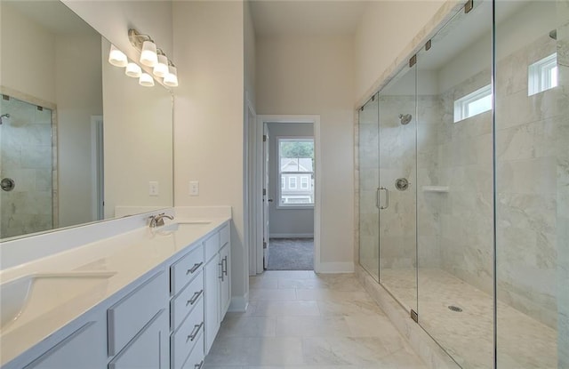 bathroom featuring a shower stall, double vanity, baseboards, and a sink