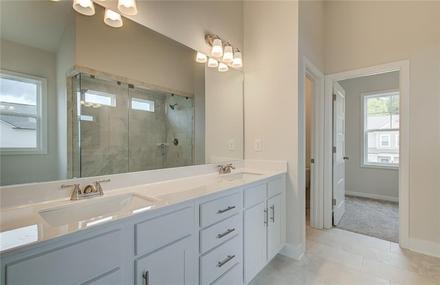 full bathroom with double vanity, baseboards, a stall shower, and a sink