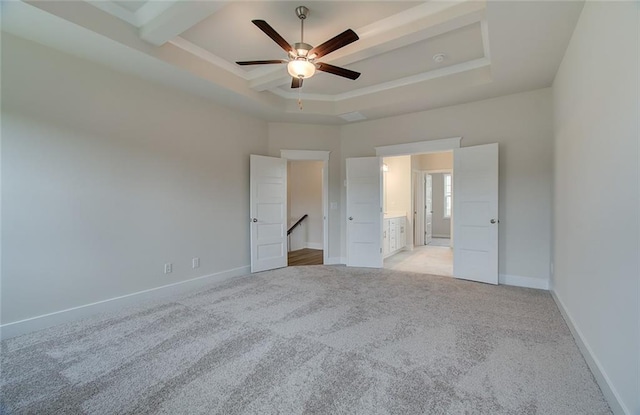 unfurnished bedroom with connected bathroom, baseboards, ceiling fan, light colored carpet, and a tray ceiling