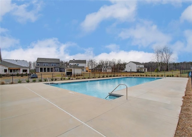 community pool with a patio area and fence