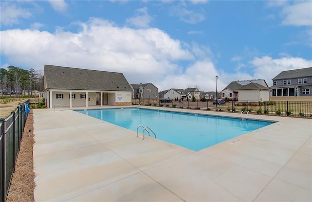 community pool featuring a patio area, a residential view, and fence