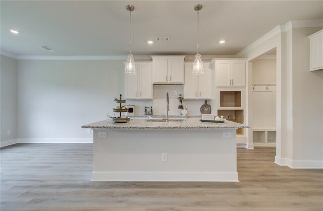 kitchen with white cabinetry, light wood-style flooring, a kitchen island with sink, and a sink