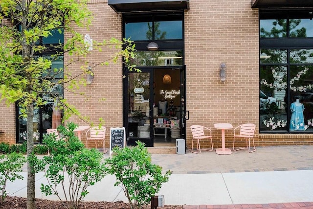 view of exterior entry featuring brick siding and a patio area