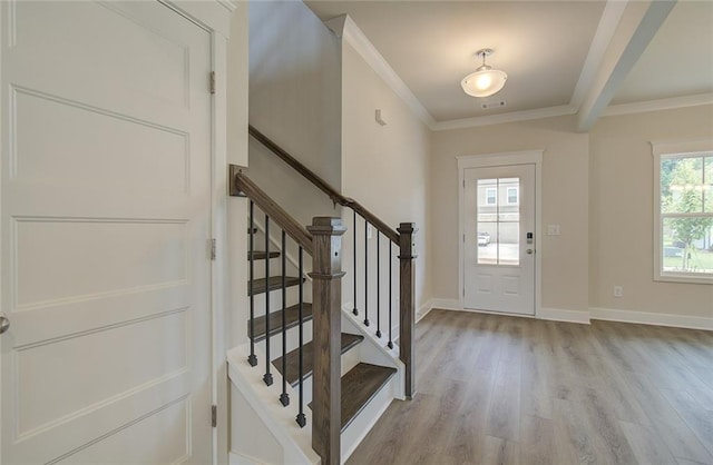 foyer entrance featuring visible vents, baseboards, ornamental molding, stairs, and light wood-style floors