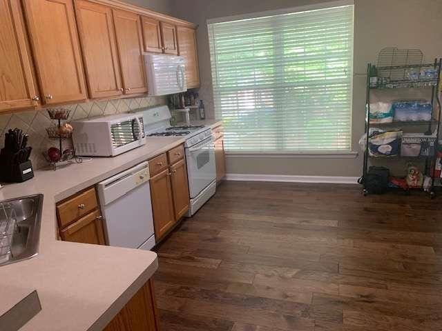 2253 Dillard Xing, Tucker, GA 30084 - kitchen with baseboards, backsplash, white appliances, light countertops, and dark wood-type flooring