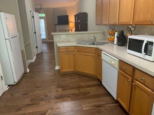 2253 Dillard Xing, Tucker, GA 30084 - kitchen with a peninsula, dark wood-style floors, a sink, tasteful backsplash, and white appliances