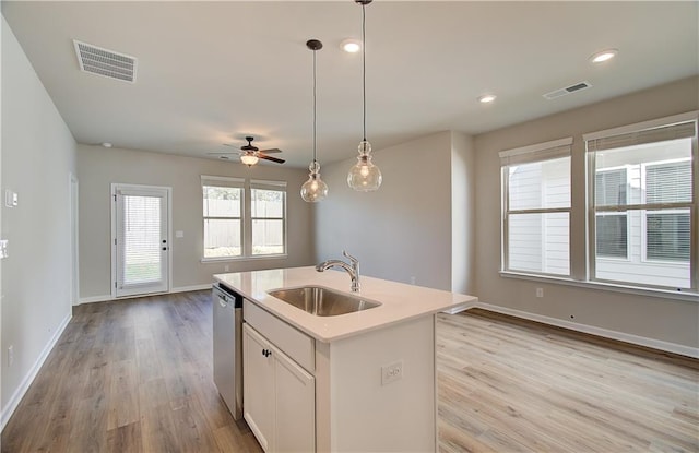 kitchen with white cabinetry, an island with sink, sink, dishwasher, and pendant lighting