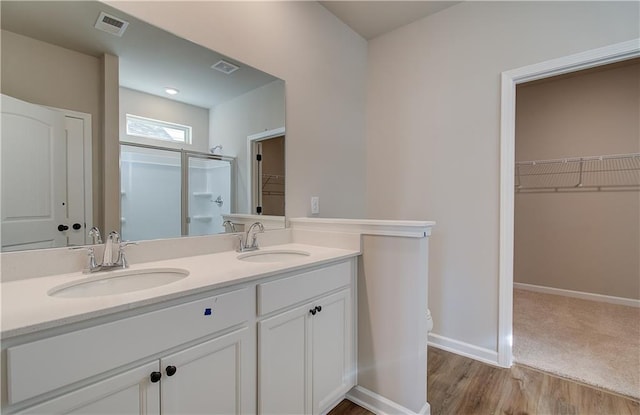 bathroom featuring hardwood / wood-style flooring, a shower with door, and vanity