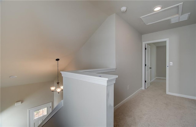 hallway with an inviting chandelier and light colored carpet