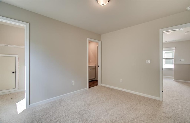 unfurnished bedroom featuring light carpet and ensuite bathroom