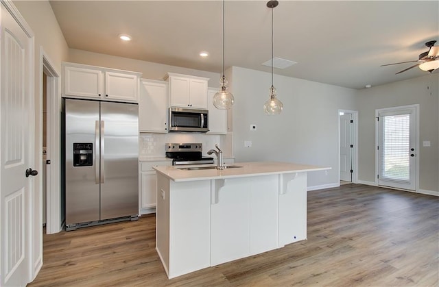 kitchen featuring white cabinetry, an island with sink, stainless steel appliances, sink, and pendant lighting