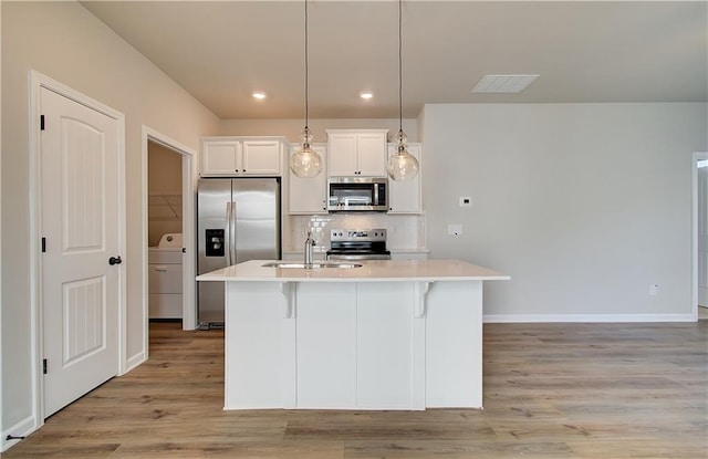 kitchen with a center island with sink, pendant lighting, stainless steel appliances, and sink