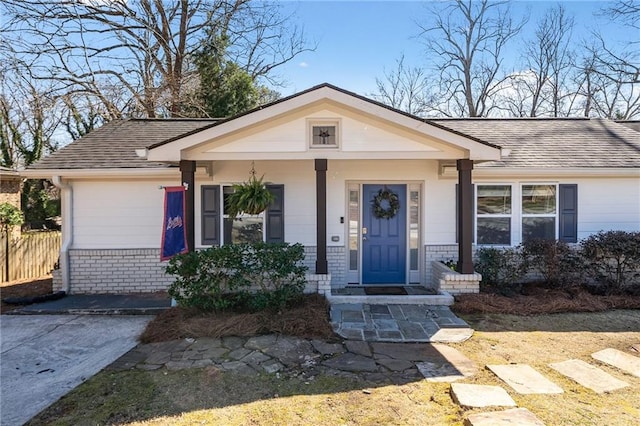 view of front of property with driveway, brick siding, and roof with shingles