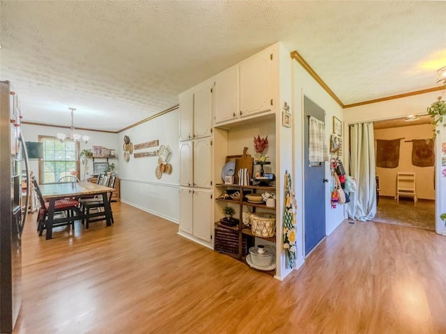 3769 Bay Creek Church Rd, Loganville, GA 30052 - kitchen featuring a chandelier, ornamental molding, a textured ceiling, light wood finished floors, and white cabinets