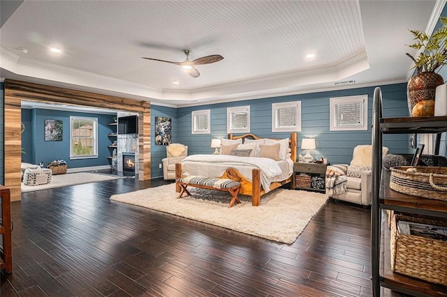 4435 Mossbrook Cir, Alpharetta, GA 30004 - bedroom with a tray ceiling, crown molding, wood finished floors, ceiling fan, and a warm lit fireplace