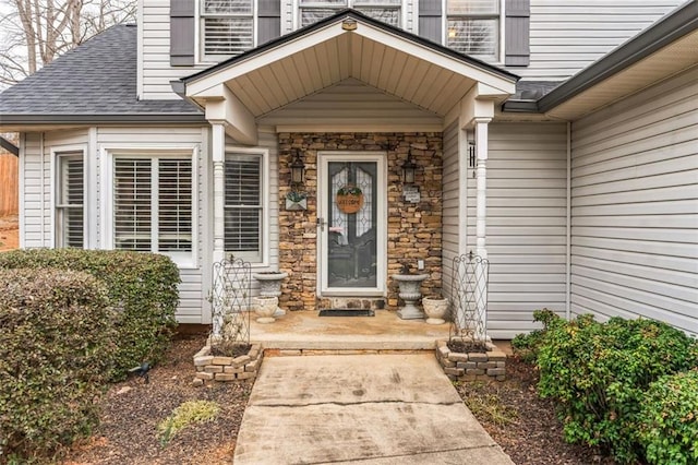 entrance to property with stone siding and roof with shingles