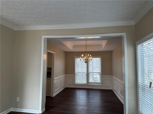 unfurnished dining area featuring a chandelier, a raised ceiling, dark wood finished floors, and a textured ceiling