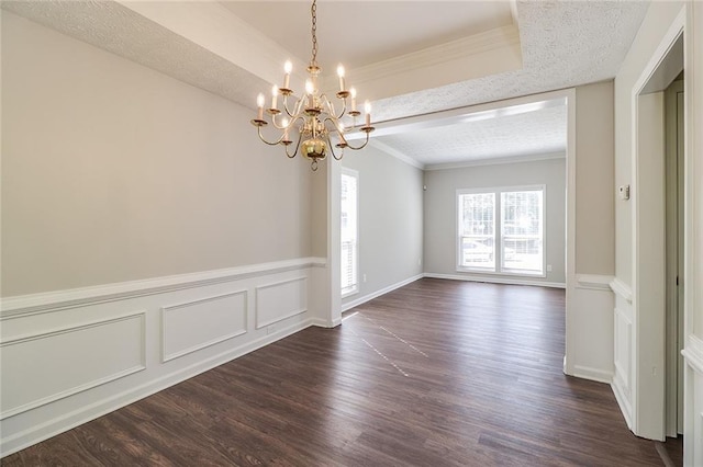 spare room with dark wood-type flooring, a tray ceiling, a chandelier, and crown molding