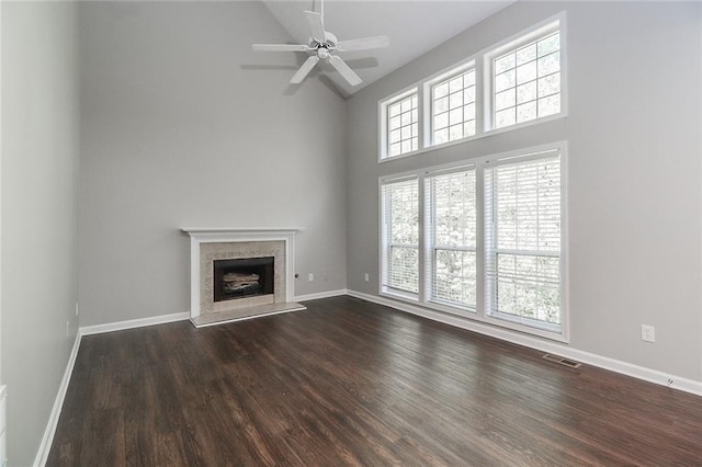 unfurnished living room featuring dark wood finished floors, visible vents, baseboards, a fireplace, and high vaulted ceiling
