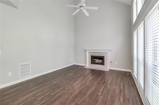 unfurnished living room featuring dark wood-style floors, baseboards, visible vents, high vaulted ceiling, and a fireplace