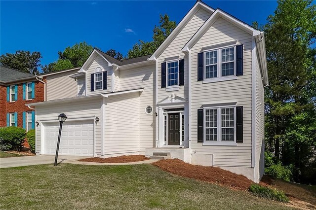 traditional-style house with a front lawn, driveway, and a garage