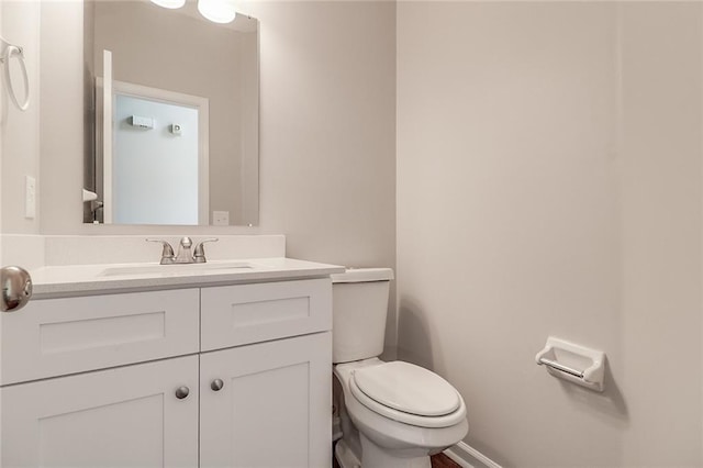 half bathroom with toilet, vanity, and baseboards