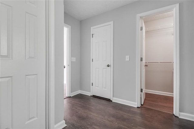 interior space featuring dark wood-type flooring, a textured ceiling, and baseboards